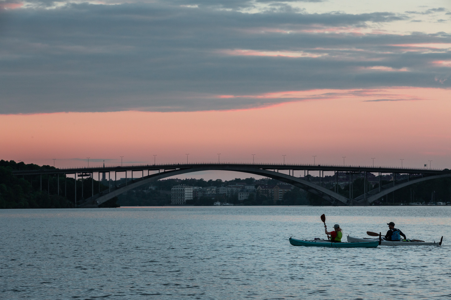 Kajakpaddlare med västerbron i bakgrunden i solnedgång